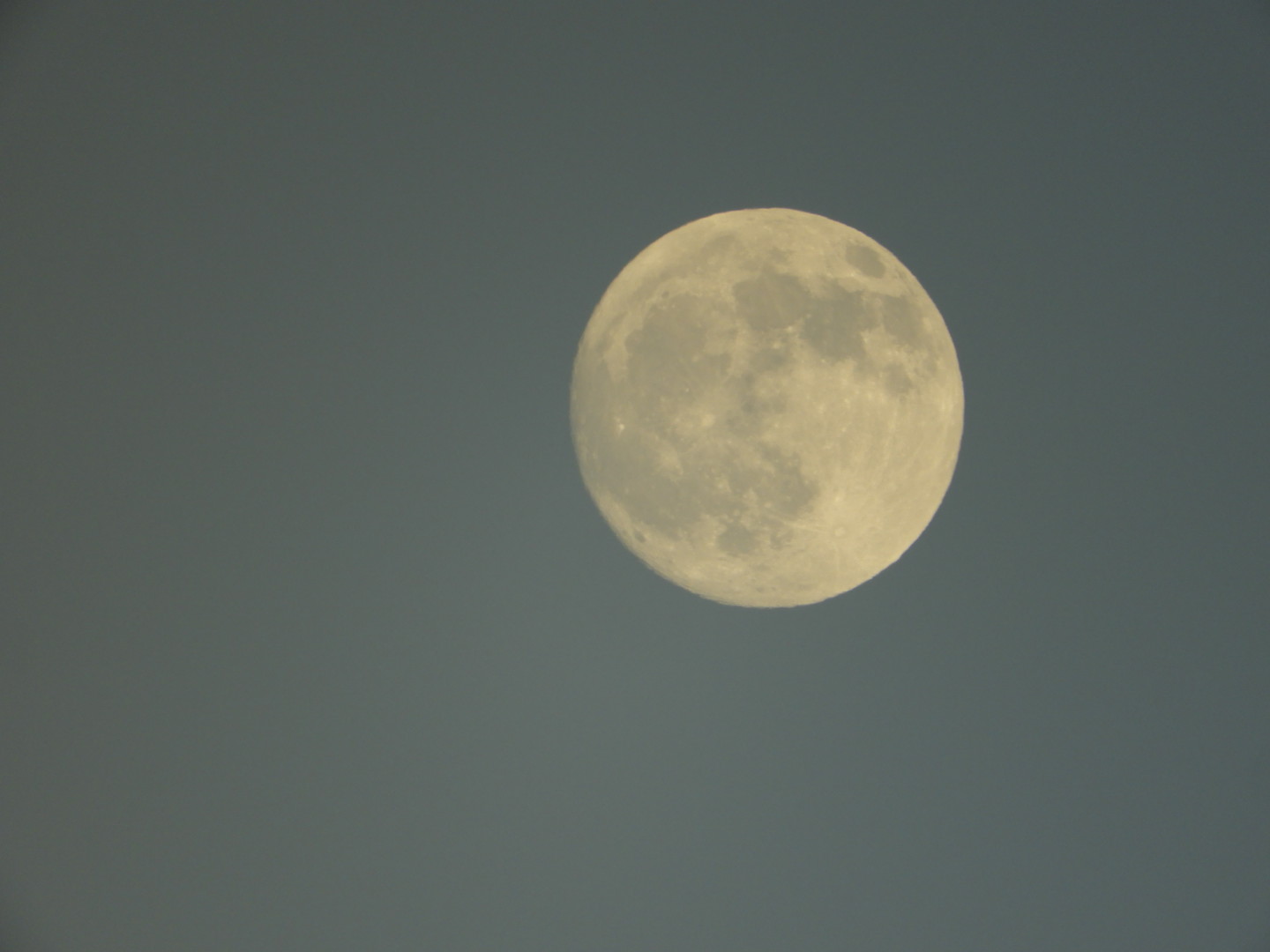 Full Moon with craters and moonscape clearly visible against a grey sky