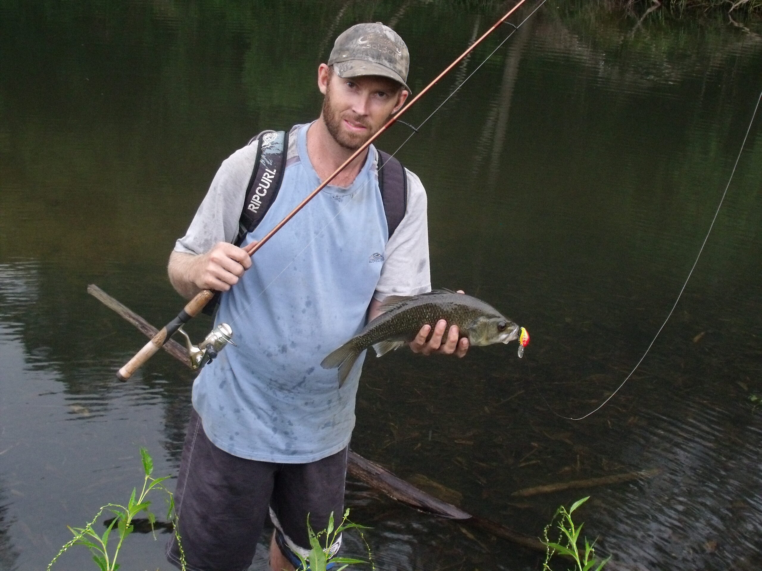 Man with fishing rod and large bass in his hand looking happy